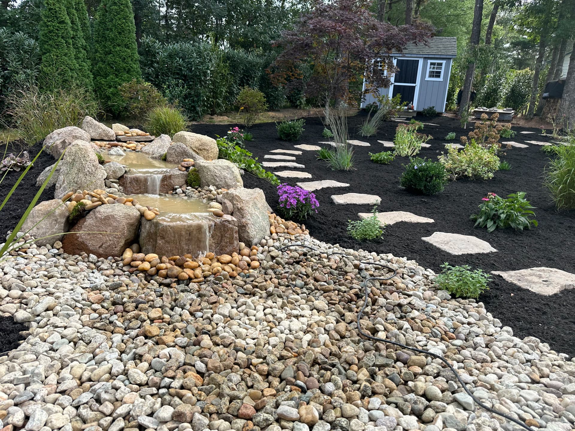 Waterfall, Perennial Garden and Stepping Stone Path Backyard Makeover image